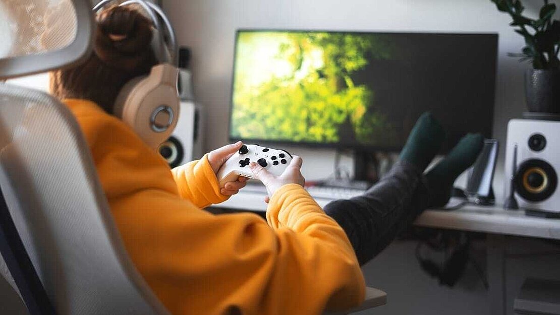 Serious Games für Jugendliche Jugendliche spielt mit Controller am PC