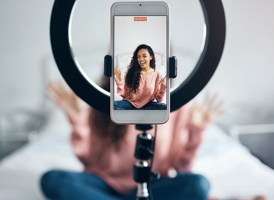 Traumberuf Influencerin? Junge Frau nimmt Video mit Smartphone und Ringlicht auf