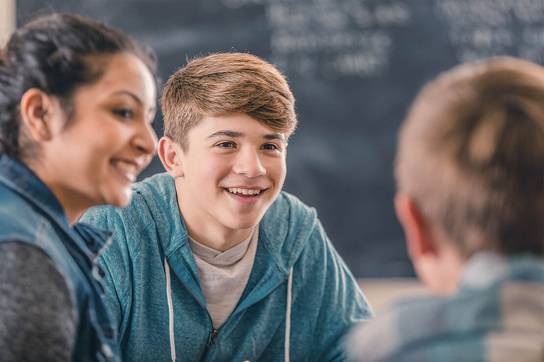 Bei den Net-Piloten mitmachen Drei Jugendliche unterhalten sich im Klassenraum