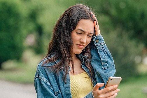 Mädchen schaut besorgt auf Smartphone