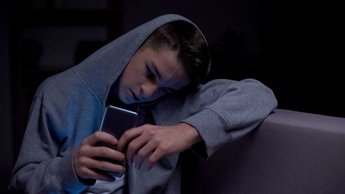 Pornosucht bei Jugendlichen Junge schaut gebannt aufs Smartphone