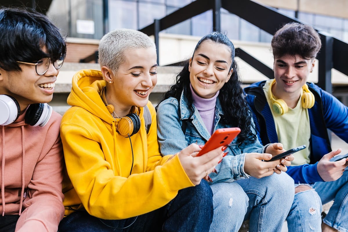 Vier Jugendliche lachend mit Smartphones in den Händen.